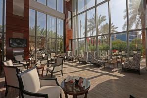 a lobby with chairs and tables and windows at Qaser Alhamra Hotel Riyadh in Riyadh