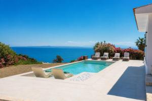a pool with chairs and the ocean in the background at Xenia Sea view Villa in Argassi +35 photos