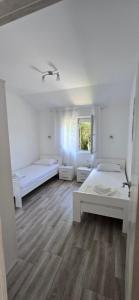 a white room with two beds and a window at Apartmani Furesti 2 in Donji Stoliv