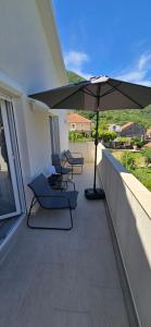 a balcony with two chairs and an umbrella at Apartmani Furesti 2 in Donji Stoliv