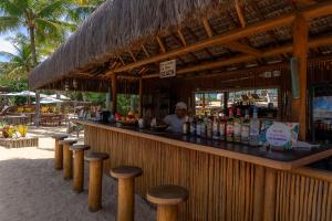 a bar in a resort with a man standing behind it at Hotel e Resort Villas de Trancoso in Trancoso