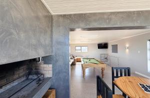 a living room with a fireplace and a pool table at Franskraal Zeehoek in Franskraalstrand