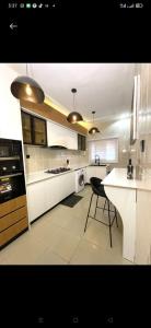 a kitchen with white cabinets and a black chair at Dee's Apartment in Gwarinpa