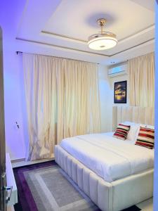 a bedroom with a large white bed with curtains at Dee's Apartment in Gwarinpa