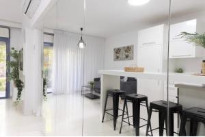 a white kitchen with black stools and a counter at רויאל דרים אילת in Eilat