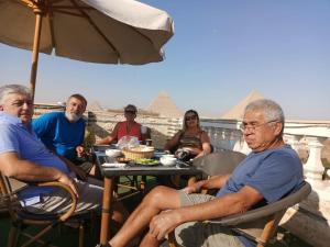 a group of people sitting at a table with pyramids in the background at Magic pyramids star hotel in Cairo