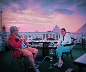 two women sitting in chairs in front of the pyramids at Magic pyramids star hotel in Cairo