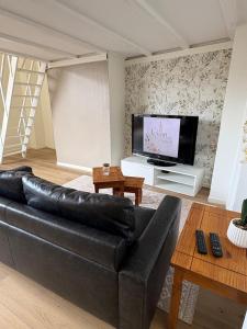 a living room with a black leather couch and a flat screen tv at Le Cocon de St-Pierre in Calais