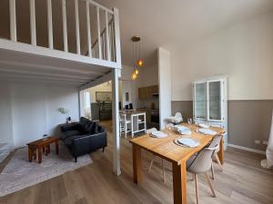 a dining room and living room with a table and a couch at Le Cocon de St-Pierre in Calais
