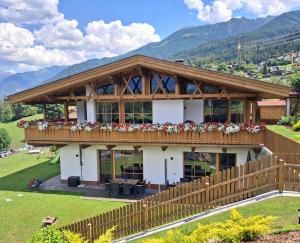 a house in the mountains with a wooden fence at Landhaus Eiter in Arzl im Pitztal