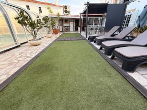 a patio with chairs and a green lawn at Dii Beach House - Piscina Aquecida 28º-32º C in Torres Vedras