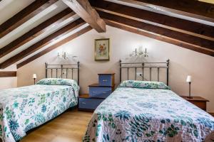 two beds in a attic room with wooden ceilings at Casa Santa Leocadia in Tama