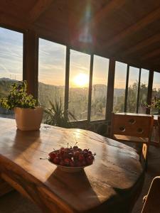 a wooden table with a bowl of cherries on it at Lodges VEIS in Kamenicë