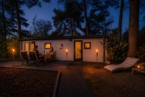 a couple sitting at a table in front of a tiny house at Sfeervol boshuisje op de Veluwe Vossenberg in Nunspeet