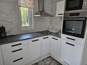 a white kitchen with white cabinets and a microwave at Loni in Klenovica