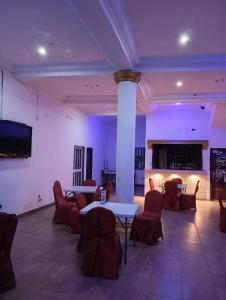 ein großer Raum mit Tischen und Stühlen und einem Fernseher in der Unterkunft Embel Hotel in Port Harcourt