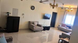 a living room with two chairs and a tv at شقة كبيرة مؤثثة بالكامل in Salalah
