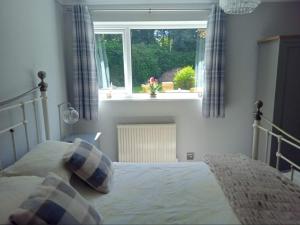 a bedroom with a bed in front of a window at 2 Bedroom Garden Flat in Halesworth