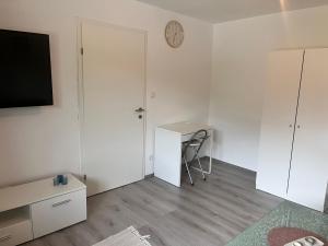 a small white room with a desk and a clock on the wall at Ferienhaus Michi in Ursprung