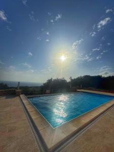 a large swimming pool with the sun in the sky at Villa D'aragona Windmill in Għajnsielem