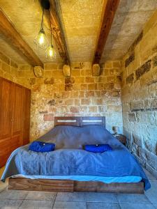 a bedroom with a blue bed in a stone wall at Villa D'aragona Windmill in Għajnsielem