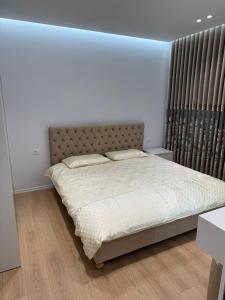 a bed in a white room with a bedvisor at Apartment 51 Luxury in Kamëz