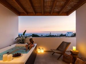a woman sitting in a bath tub on a balcony at Vendema Residence Mykonos in Mikonos