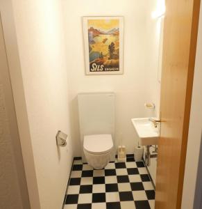 ein Badezimmer mit Toilette und Schachbrettboden in der Unterkunft Viamalablick in Thusis