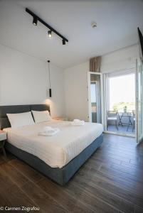 a bedroom with a large bed and a balcony at Costa Varda Apartments in Mourteri
