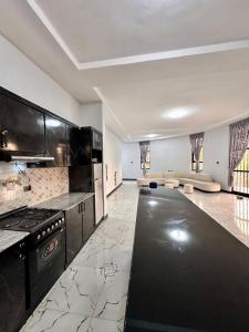 a large kitchen with black cabinets and a living room at Hilm cottage in Āwasa