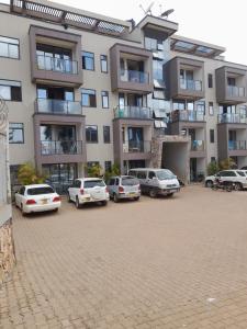a parking lot with cars parked in front of a building at Ebenezer Apartment, Albert Cook Road in Kampala