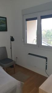 a bedroom with a bed and a window and a chair at Apt Moravica in Soko Banja