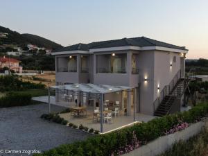 a large white house with a table and chairs at Costa Varda Apartments in Mourteri