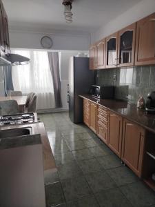 a kitchen with wooden cabinets and a black refrigerator at Apartament OAȘUL 2 in Hurez