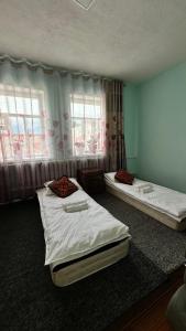 two beds in a room with two windows at datkaguesthouse in Kochkorka
