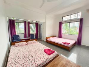 a bedroom with two beds and two windows at Taj Heritage Hotel and Restaurant - Premium & Budget Rooms in Jorhāt +15 photos