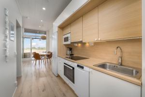 a kitchen with white cabinets and a sink and a table at Apartment Aurinkoranta D5 saunallinen kaksio merinäkymällä Kalajoki in Kalajoki