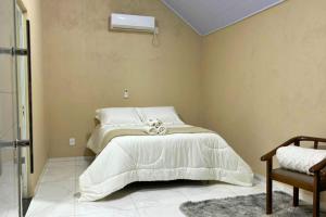 a bedroom with a white bed and a air conditioner at Chalés EduCarMo in Ametista do Sul