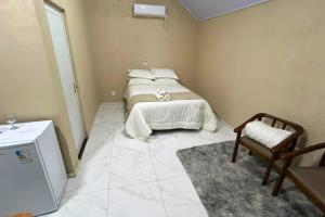 a bedroom with a bed and a chair in it at Chalés EduCarMo in Ametista do Sul