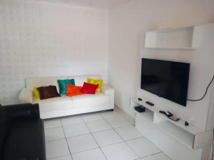 a living room with a white couch with colorful pillows at recanto sossego in Garanhuns