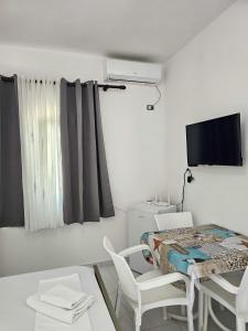a white room with a table and chairs and a tv at Troi beach house in Vlorë