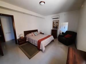 a bedroom with a bed and a couch and a chair at Spacious Poolside Apartment with Patio 11A2S in Għajnsielem +28 photos