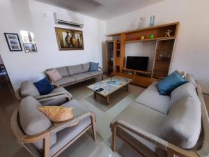 a living room with two couches and a tv at Spacious Poolside Apartment with Patio 11A2S in Għajnsielem