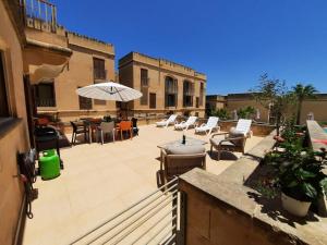 an outdoor patio with chairs and tables and an umbrella at Spacious Poolside Apartment with Patio 11A2S in Għajnsielem