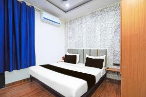 a bedroom with a large bed with a blue curtain at Hotel O The Arrow in New Delhi