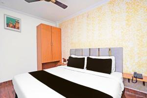a bedroom with a large white bed and yellow wallpaper at Hotel O The Arrow in New Delhi