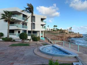a white building with a plunge pool next to the ocean at By the sea Condominium in San Carlos