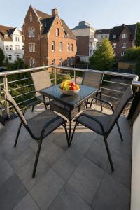 a table and chairs with a bowl of fruit on a balcony at Neubau Stadtwohnung mit Balkon in Siegen Parkplatz WLAN Autobahn in Siegen