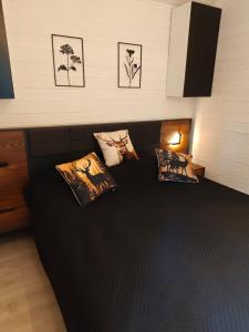 a bedroom with a black bed with pillows on it at Stacja Roztocze in Majdan Kasztelański