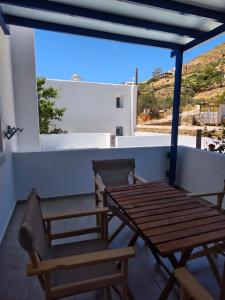 a wooden table and chairs on a balcony at Deilino - Olive View Studio in Amorgos